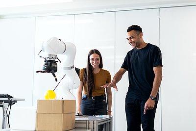 Ingenieur und Ingenieurin, die sich einen Cobot anschauen Ingenieur und Ingenieurin, die sich einen Cobot anschauen