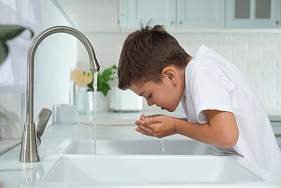 Vom Wasserhahn trinkendes Kind Vom Wasserhahn trinkendes Kind